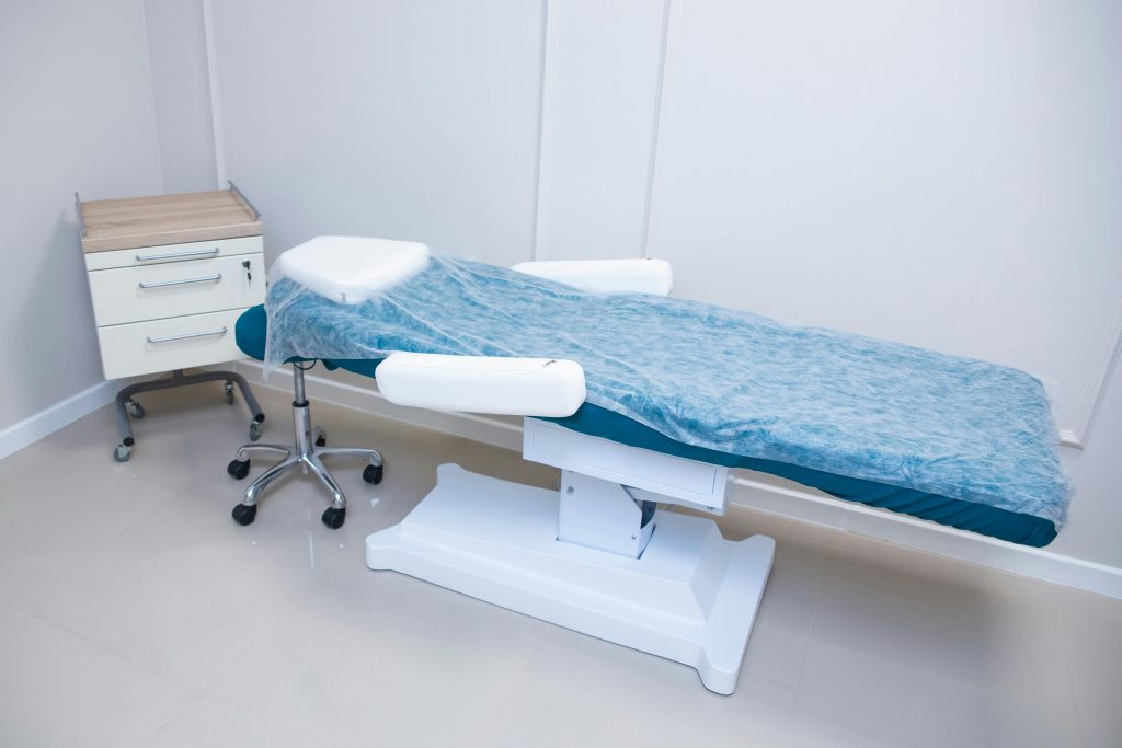 Sterile and modern medical examination room featuring adjustable bed and cabinet.
